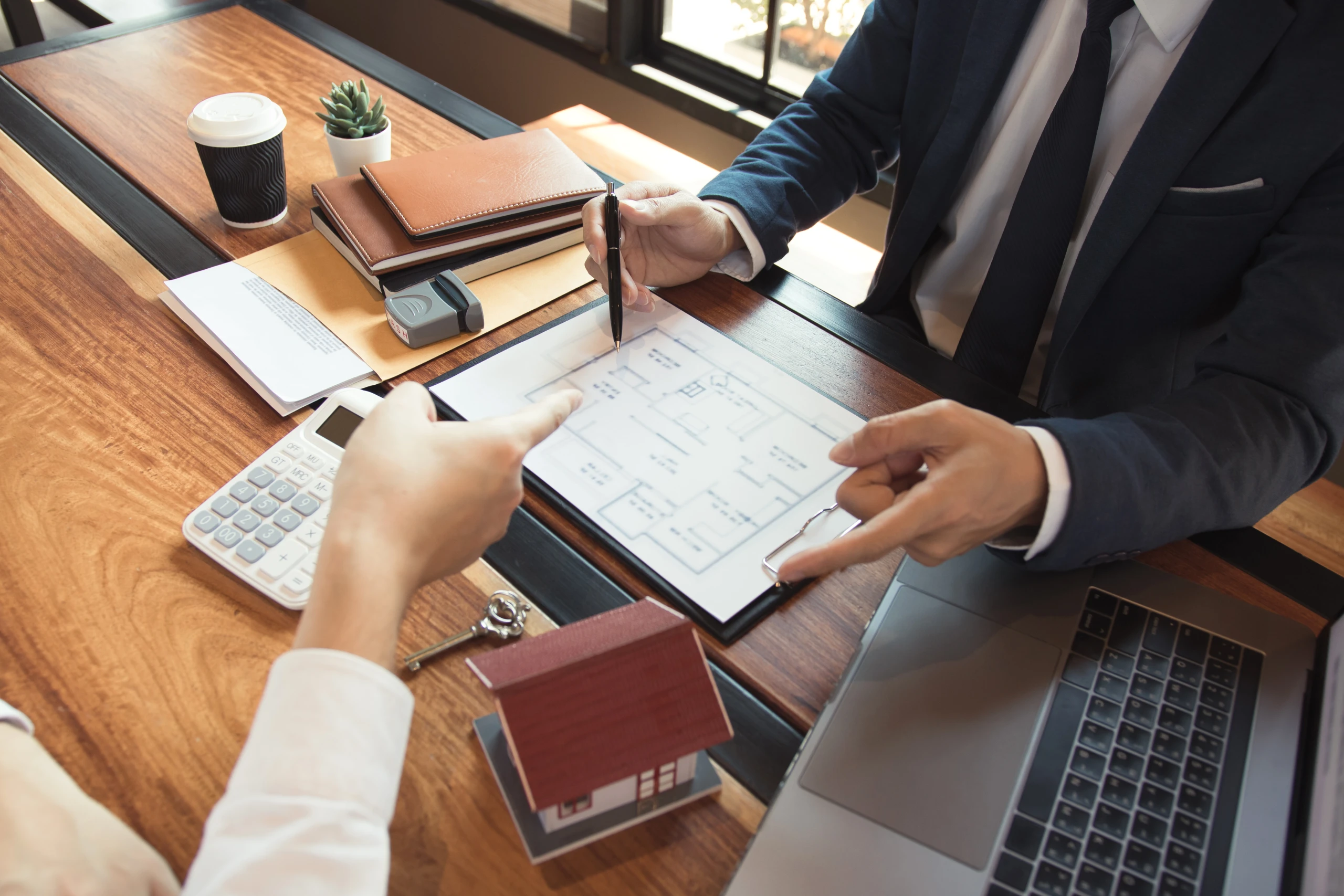 Conseil expliquant à son client le plan d'une maison et son montage fiscal